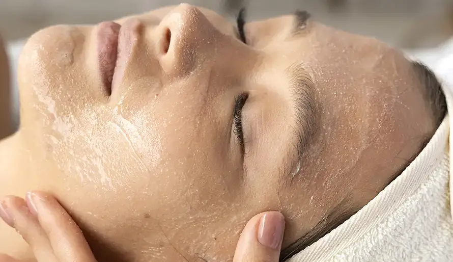 Rostro de una mujer untado en crema recibiendo un tratamiento facial estético